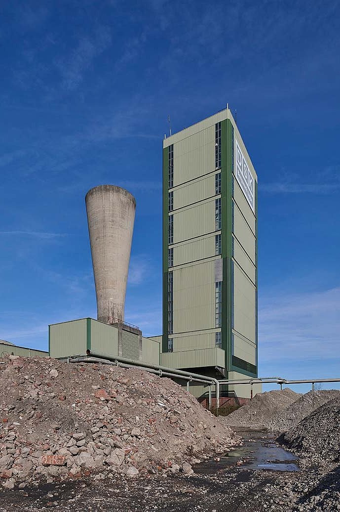 Schacht 1 Außenansicht, großes grüner Turm mit danebenliegenden konischem Turm in grau.