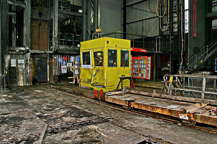 Schacht 1 Innenansicht, gelber Steuerungsraum in Halle, mehrere Männer mit gelben Helmen sind in und um den Raum zu sehen