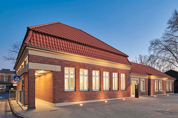 Torhaus West Außenansicht, rotes Backsteingebäude mit abendlicher Beleuchtung vor blauem Abendhimmel