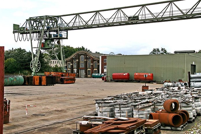 Hochregallager von außen, davor Baumaterial und ein Kran