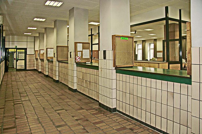 Lohn-& Lichthalle Innenansicht, weiß gefliester Flur mit grünen Durchreichen 