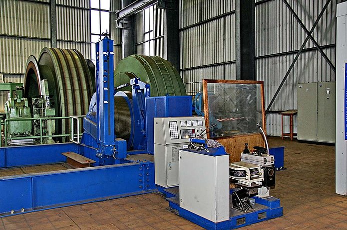 Schacht 1 Innenansicht, blaue Maschine mit Schutzwand vor dem Arbeitsplatz