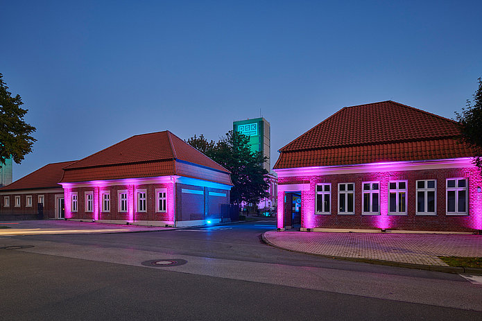 Zwei Torhäuser bei Nacht, beleuchtet von neonpinken Bodenleuchten.
